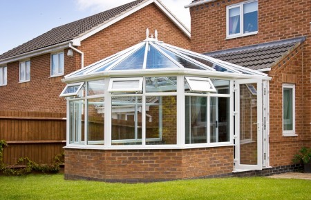 Conservatory with glass roof against a red brick house